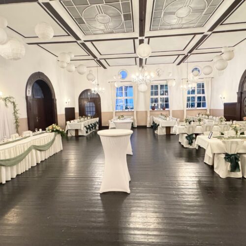 Eleganter Veranstaltungsraum mit dunklem Holzboden und weißem Dekor.
