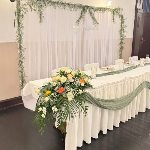 Ein elegant geschmückter Hochzeitstisch mit weißen und grünen Blumen.